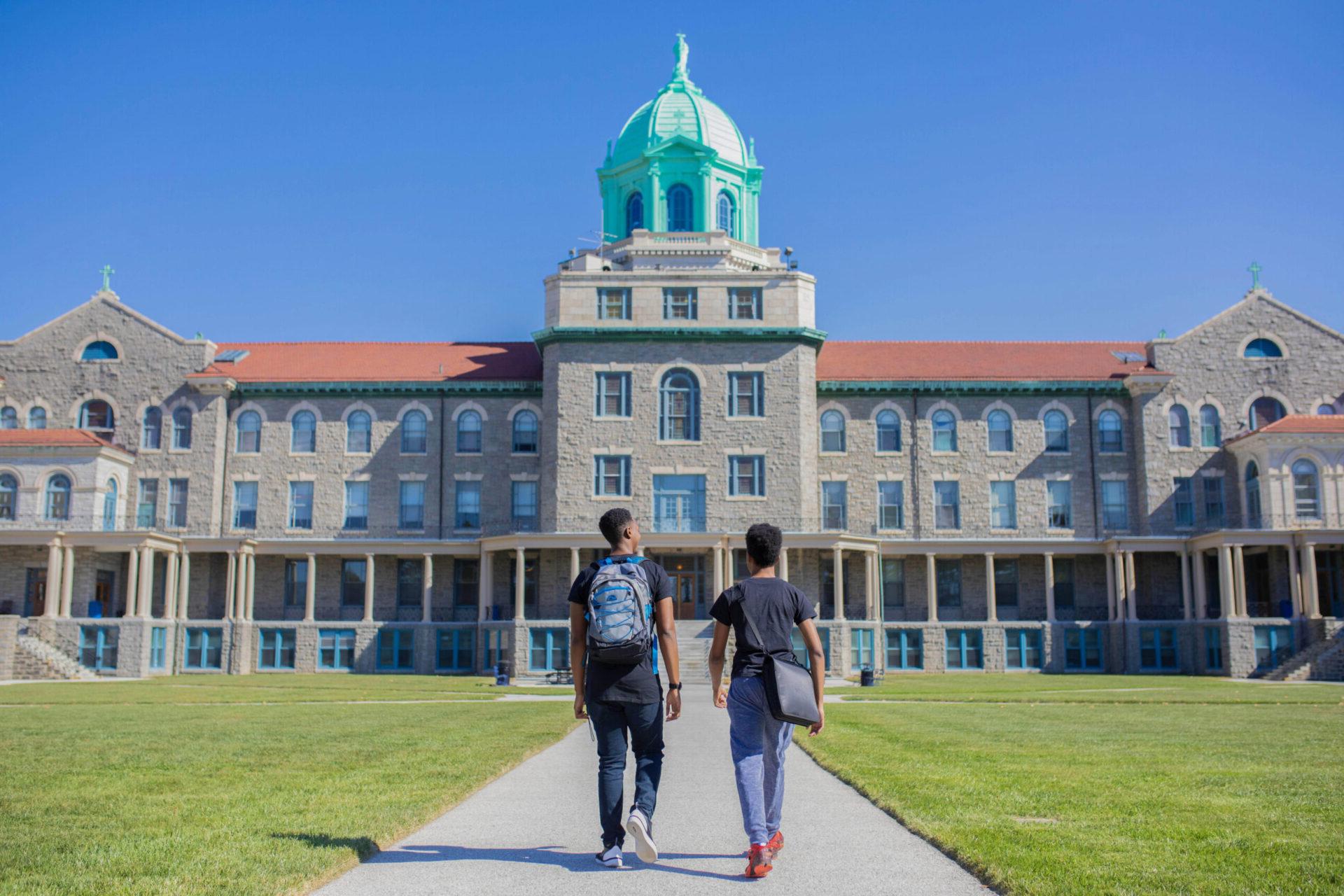 Two students walking in front of college building